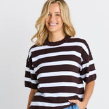 Woman wearing a black and white striped sweater and blue jeans on a plain background